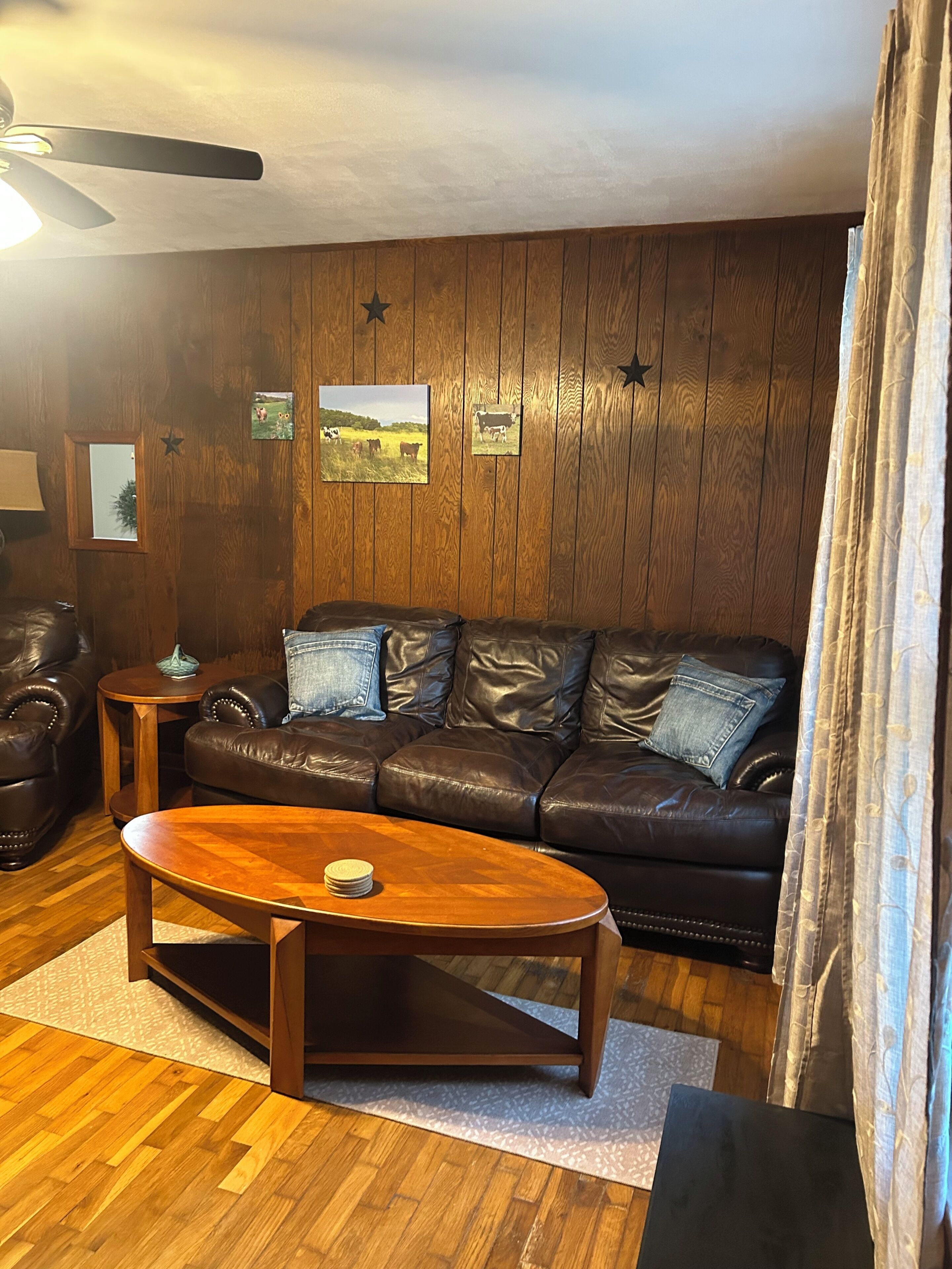 Ein Wohnzimmer mit einer Ledersofa, einem Holztisch und Bildern an der Wand.