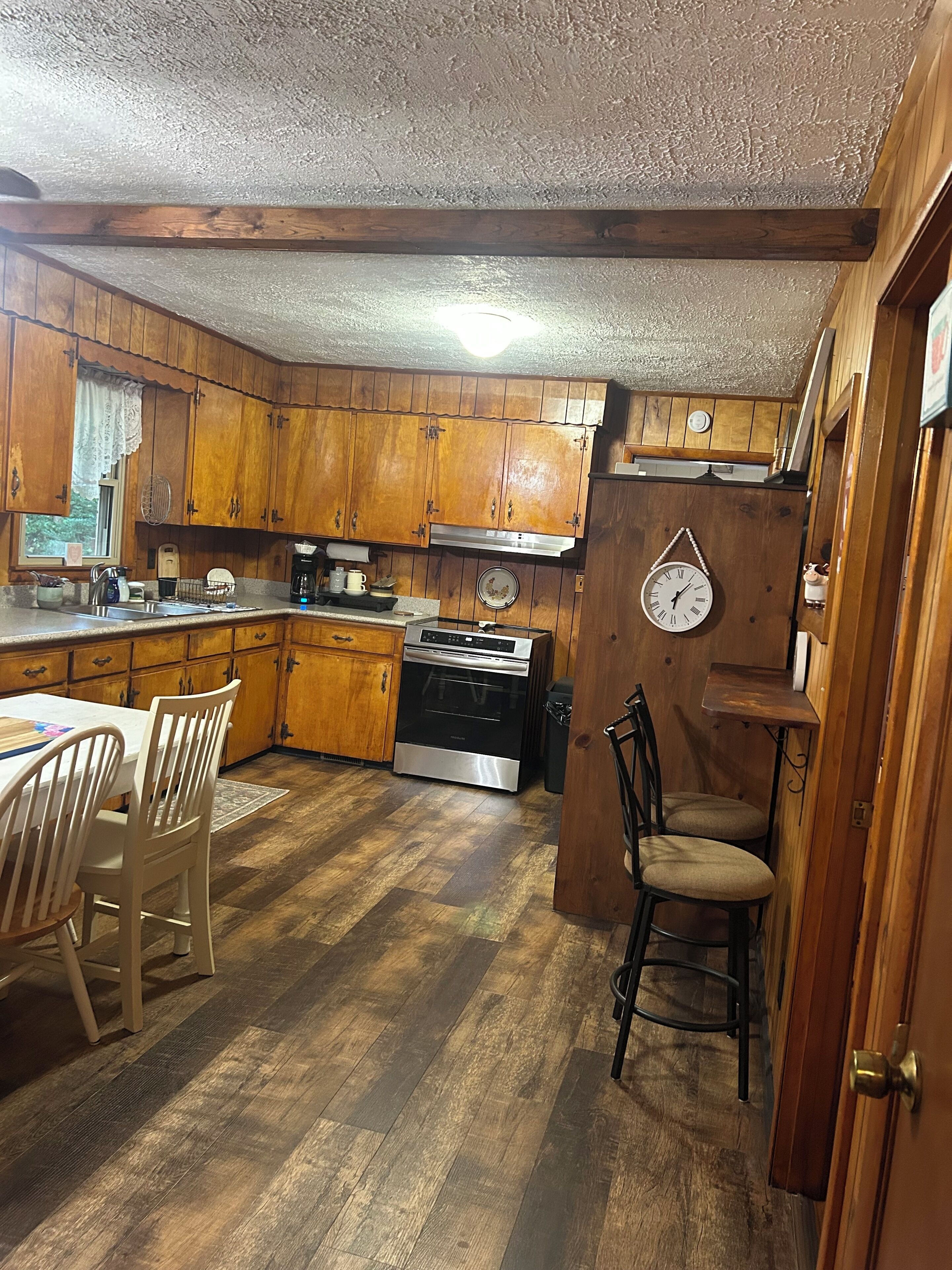 A kitchen with wooden cabinets, a stove, and a dining table with chairs.