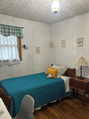 A bedroom with a bed, a nightstand, a lamp, and wall art.