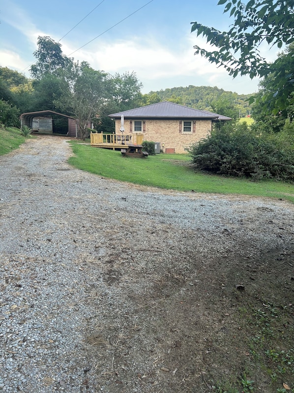 A gravel driveway leading to a house with a covered porch and a shed. - Whispering Willow Ranch House near Ethridge-home of the Amish Community (Lynnville)
