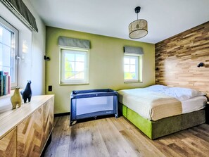 Ein Schlafzimmer mit einem Bett, zwei Fenstern, einer Holzwand und einer Deckenleuchte.