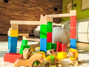 Une pièce avec une structure de jeu en bois, un canapé et un mur vert.