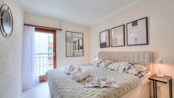 Een hotelkamer met een bed, een nachtkastje met lamp, een raam met gordijnen en kunst aan de muur.