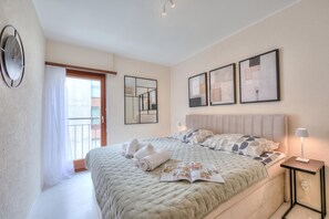 Een hotelkamer met een bed, een nachtkastje met lamp, een raam met gordijnen en kunst aan de muur.