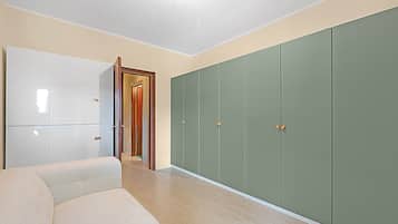 Een kamer met een bank, een kledingkast en een deur naar een andere kamer.