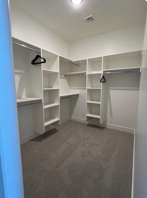 A walk-in closet with multiple shelves and hanging space.
