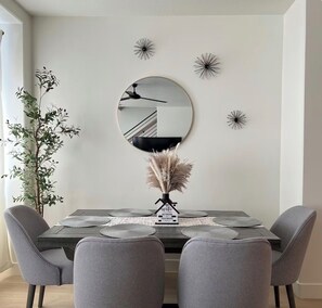 A dining area with a round mirror, decorative wall art, a potted plant, and a table set for four. - Gorgeous 3-bedroom condo in charming Cedar City perfect for relaxing (Cedar City)