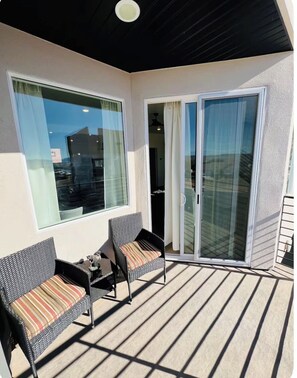 A balcony with two wicker chairs, a table, and a sliding glass door leading to an interior space. - Gorgeous 3-bedroom condo in charming Cedar City perfect for relaxing (Cedar City)