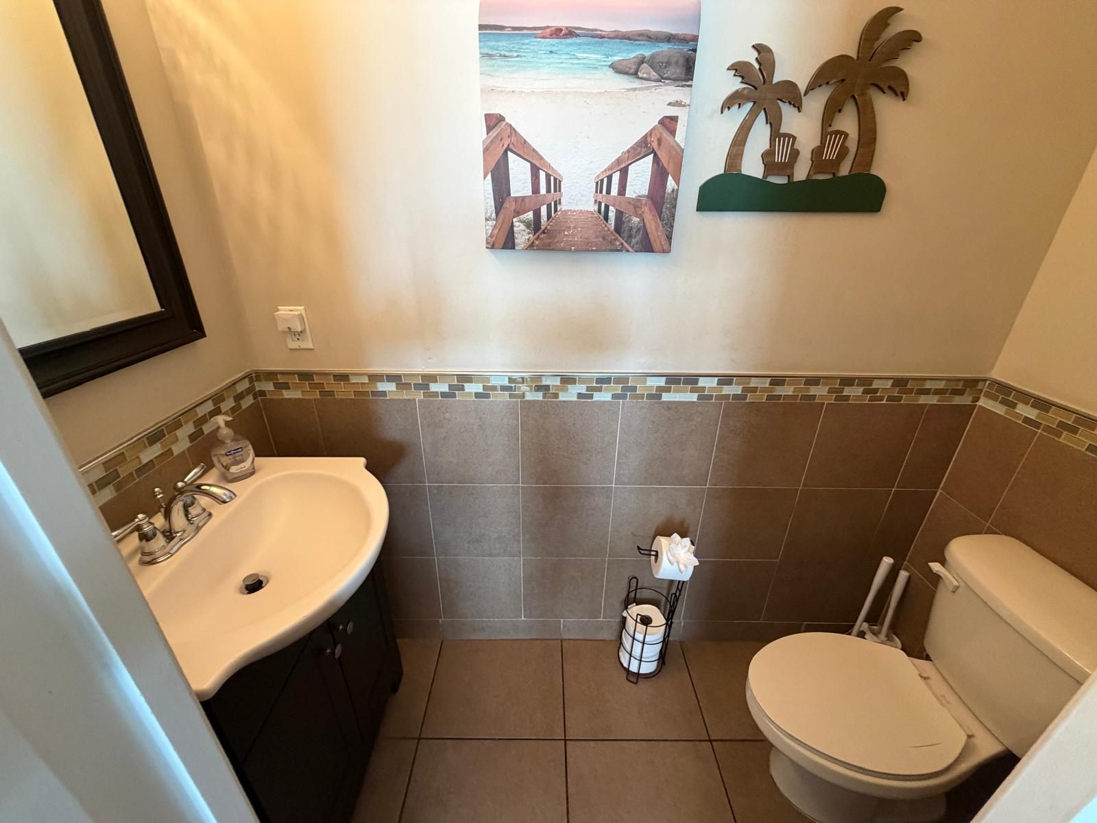 A bathroom with a sink, toilet, and a decorative wall piece.