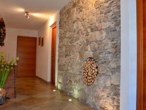 A hallway with a stone wall, wooden door, and a vase with green plants. - Chalet Appartement Hörndle in Umhausen by Interhome (Niederthai)