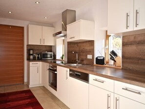 Eine moderne Küche mit weißen Schränken, Edelstahlgeräten und einer Holz Arbeitsplatte.
