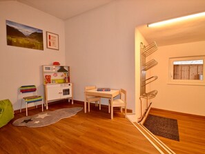 Ein Kinderzimmer mit Holzboden, einer Spielküche, einem kleinen Tisch mit Stühlen und einem Fenster mit Blick.