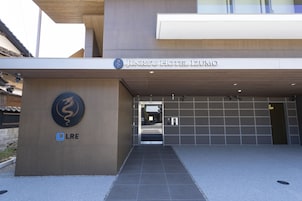 The entrance to Jinryu Hotel Izumo with a modern design, a dragon logo, and a sign for LRE.