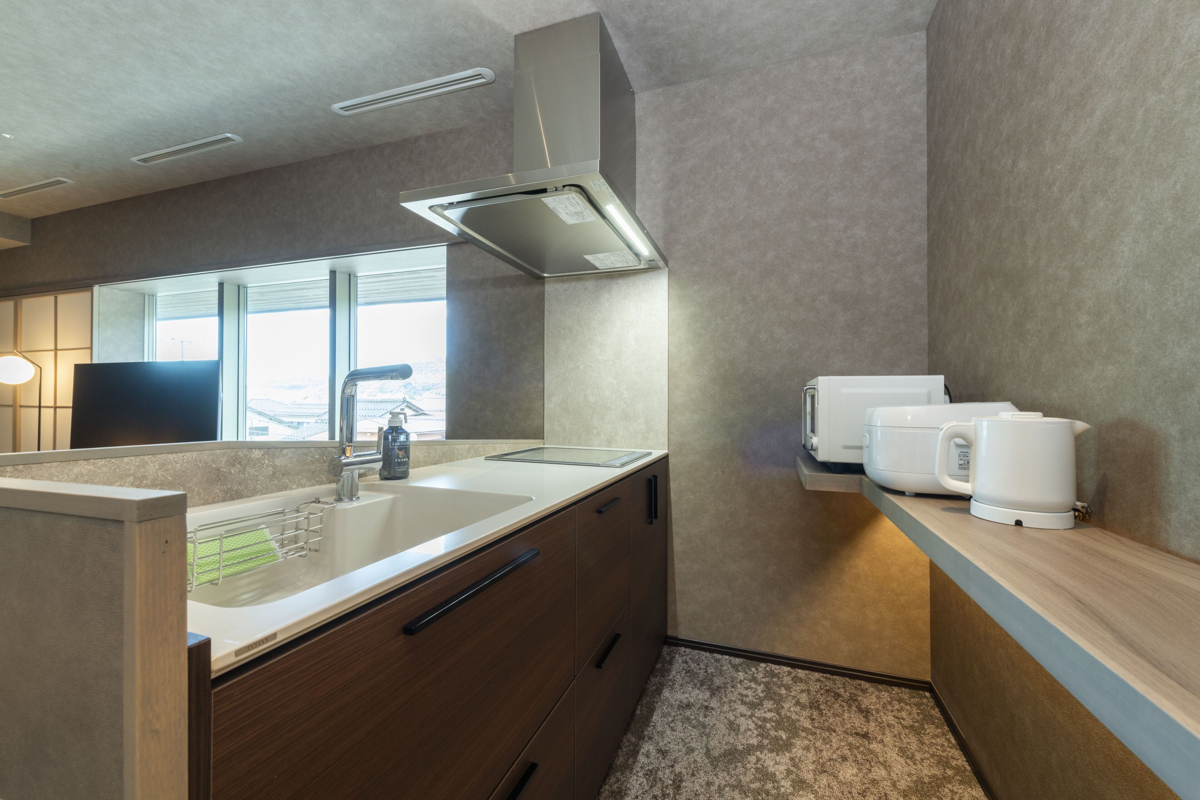 A modern kitchen with a built-in sink, a coffee machine, and a window providing natural light.