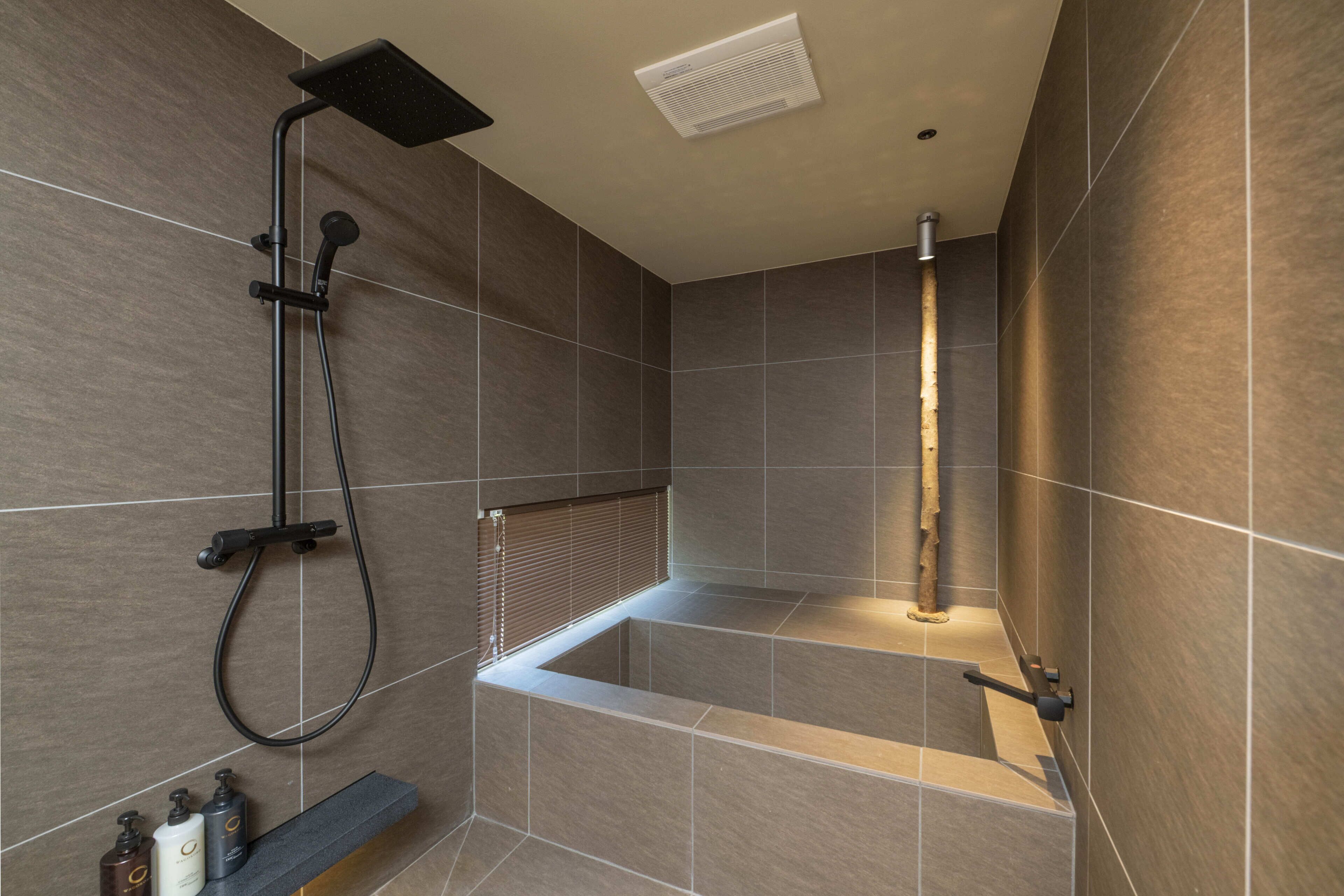 A modern bathroom with a shower, a bathtub, and a shelf with toiletries.
