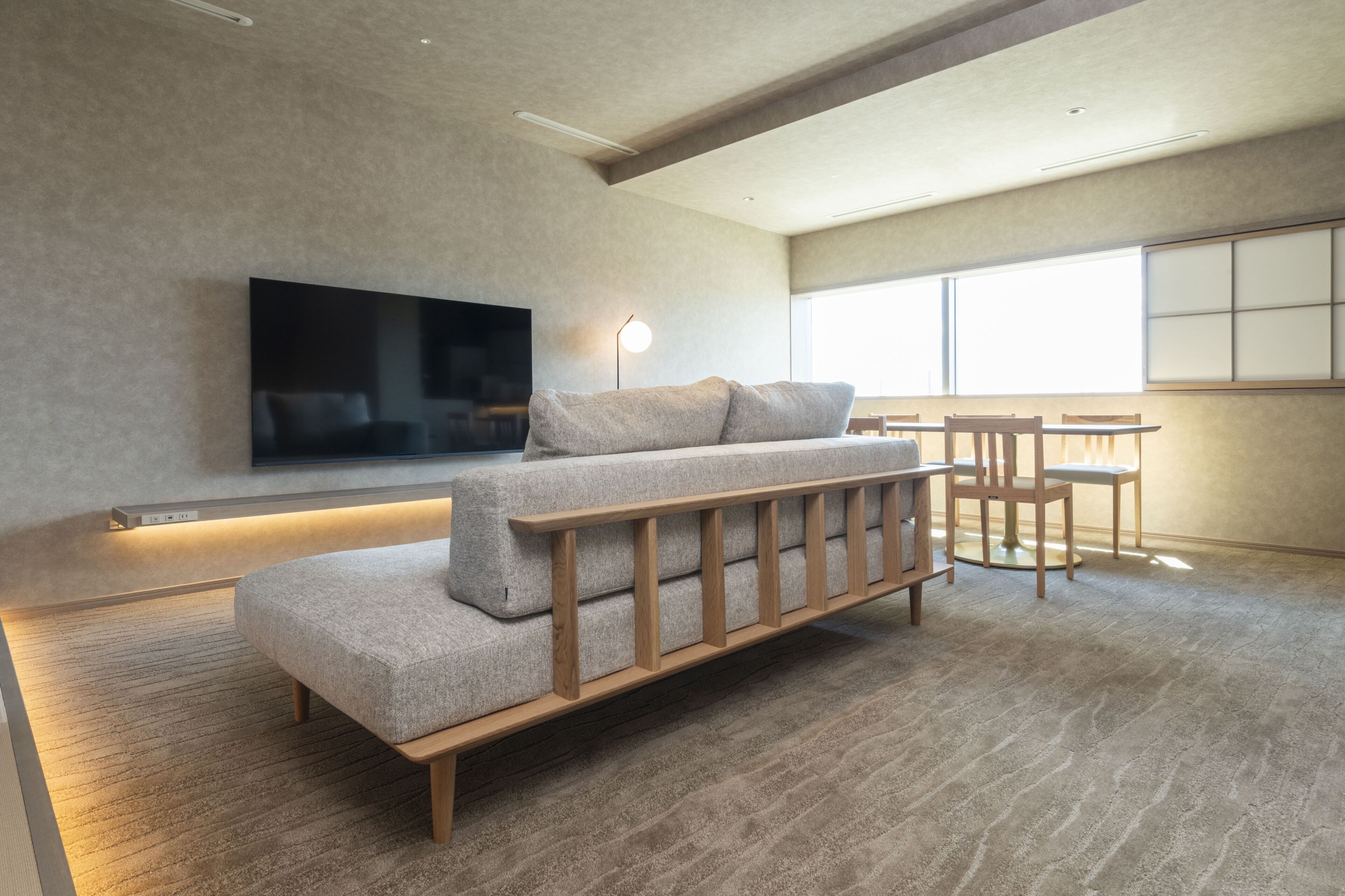 Uma sala de estar moderna com sofá, televisão de tela plana, mesa e cadeiras.