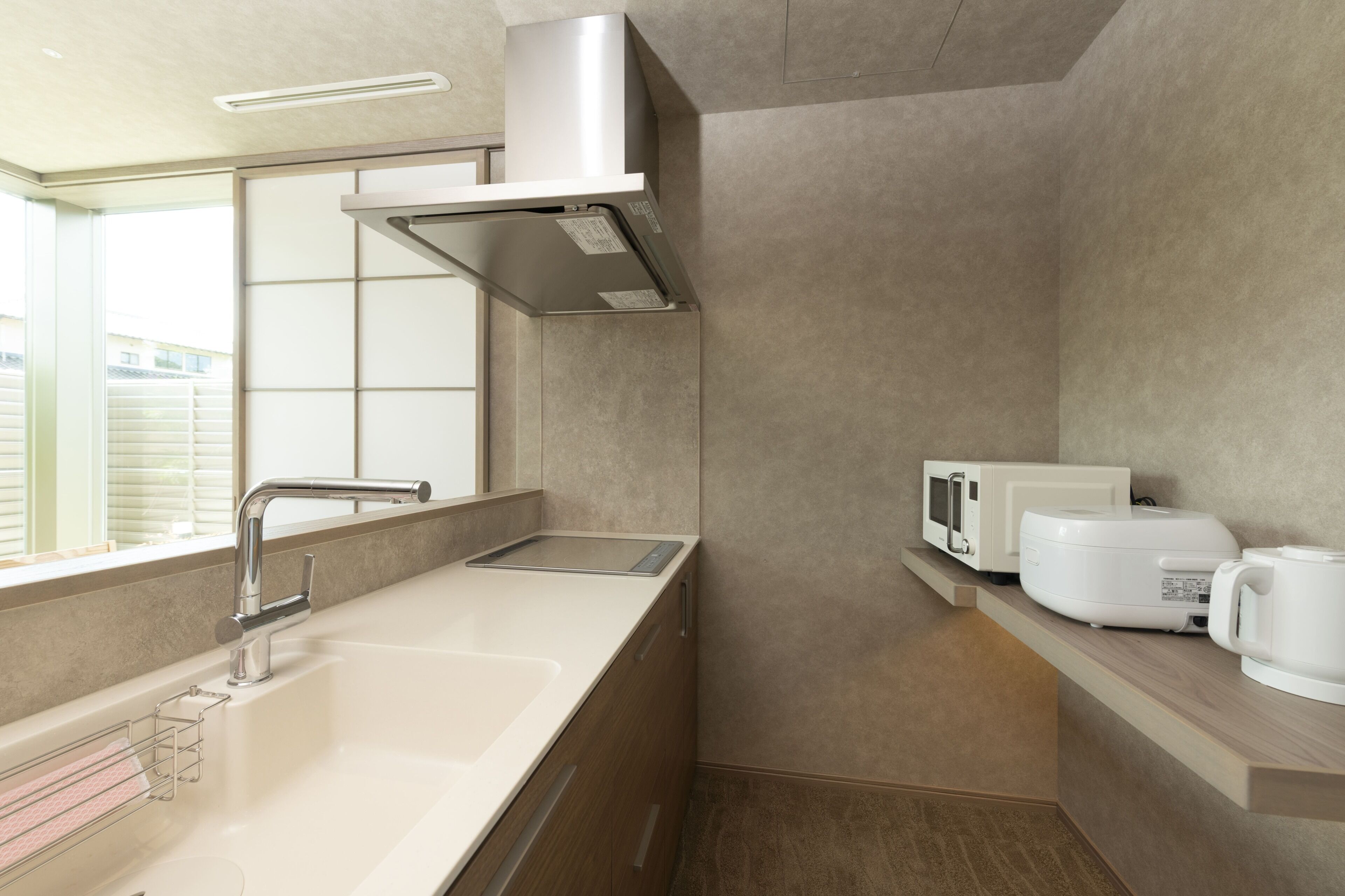 A modern kitchen with a stainless steel sink, a microwave, and a kettle on the countertop.