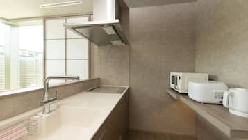 A modern kitchen with a stainless steel sink, a microwave, and a kettle on the countertop.