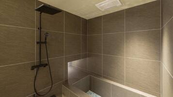 A modern shower area with a handheld showerhead and a wall-mounted control panel.