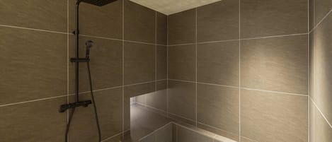 Un área de ducha moderna con un cabezal de ducha manual y panel de control en la pared.