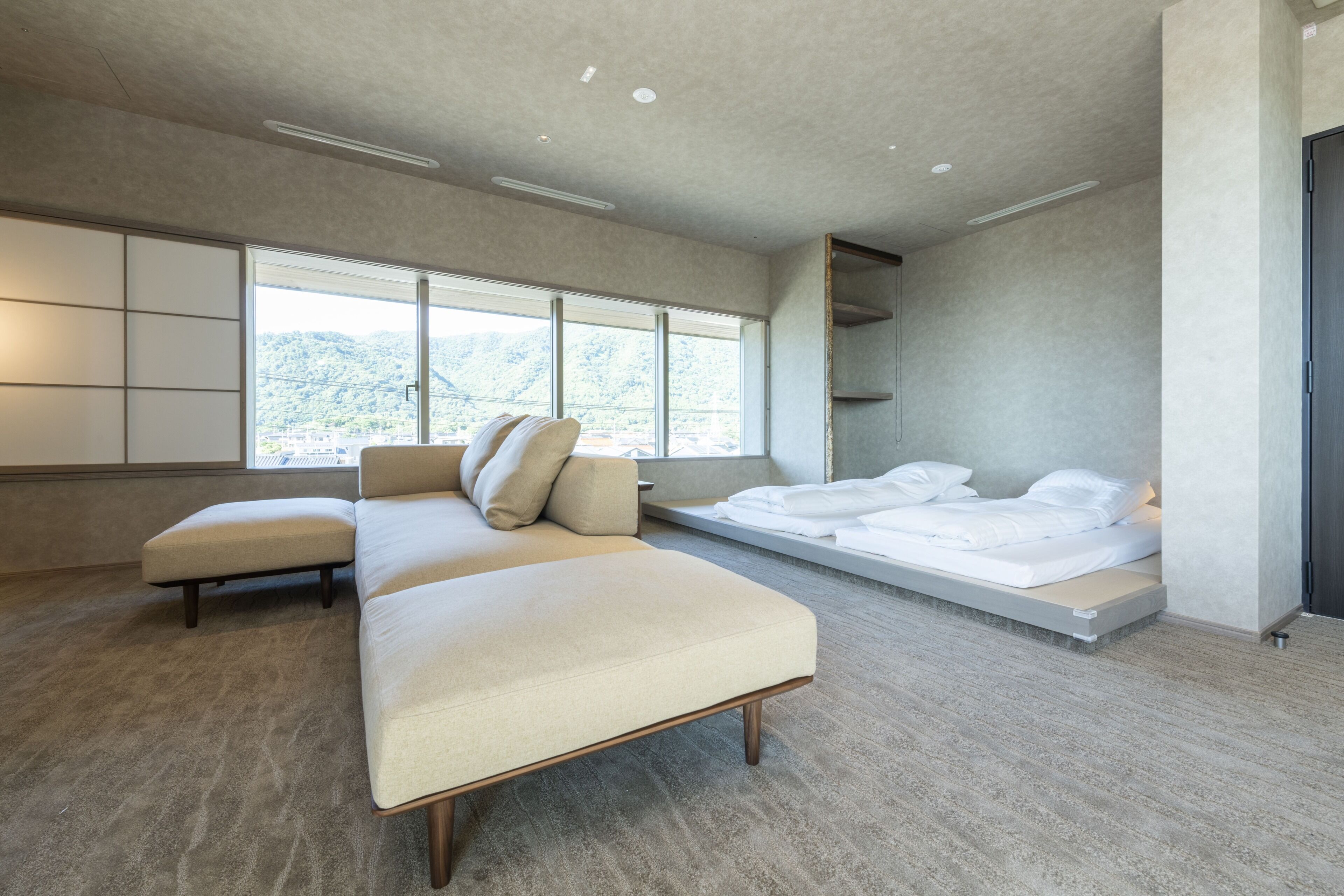 Quarto moderno com uma cama grande, um sofá e uma janela com vista para o exterior.