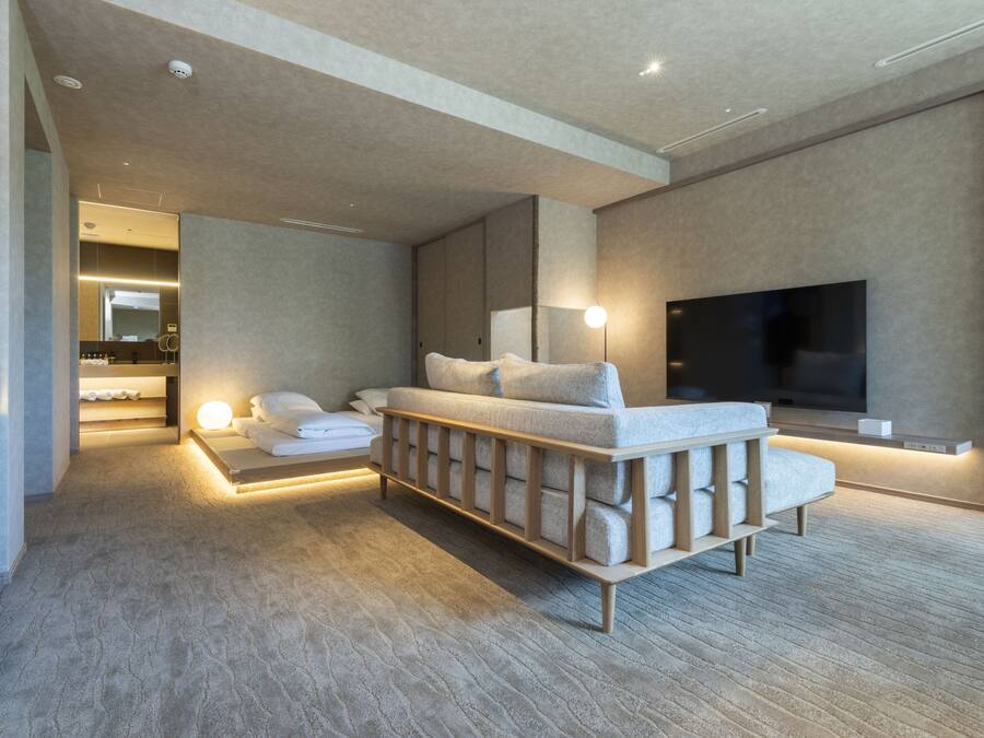 A modern hotel room with a large bed, a TV, and a seating area.