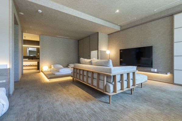 A modern hotel room with a large bed, a TV, and a seating area.