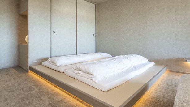 Un dormitorio minimalista con cama, armario empotrado y mesita de noche.