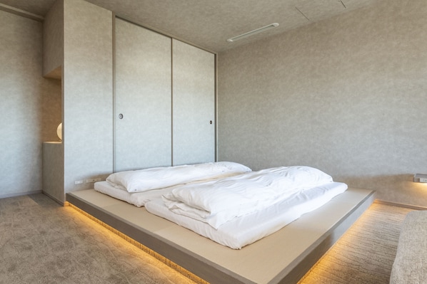 A minimalist bedroom with a bed, built-in wardrobe, and a bedside table.