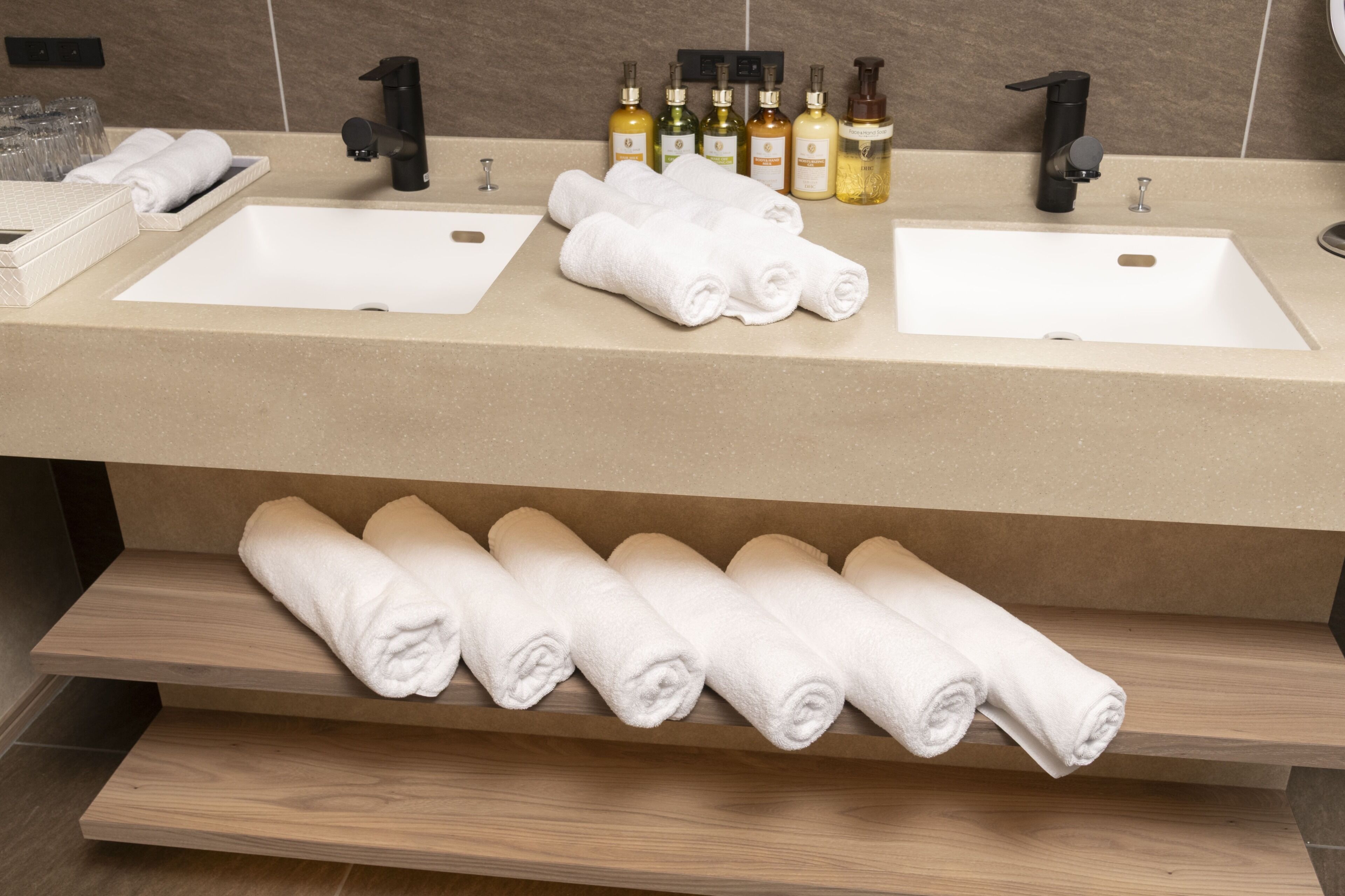 A bathroom with two sinks, a towel rack, and various toiletries.