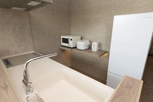 A bathroom with a sink, a microwave, and a coffee maker on a shelf.