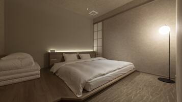 Une chambre moderne avec un lit, des tables de chevet, une lampe sur pied et une étagère intégrée.
