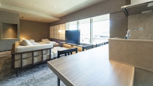Una habitación de hotel moderna con sofá, televisor de pantalla plana, mesa de comedor y zona de cocina.
