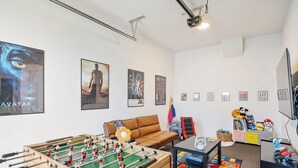 A room with a foosball table, a sofa, a television, and various posters on the walls. - Family friendly townhome + Game Room + King beds (Salem)