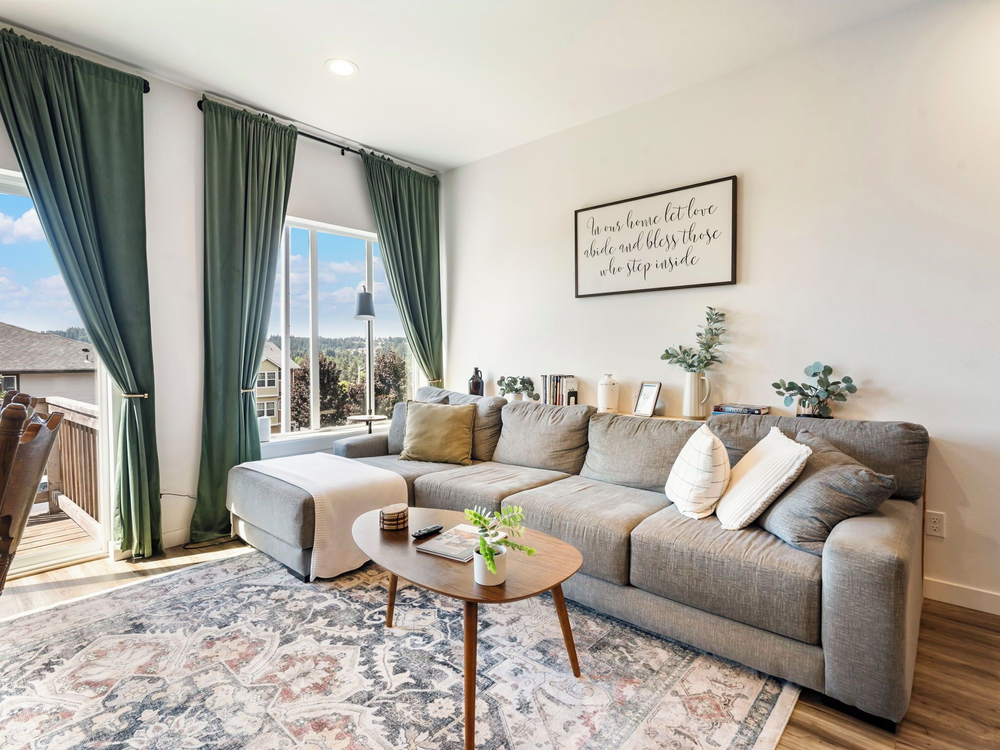 A modern living room with a sectional sofa, a coffee table, and a large window with curtains.