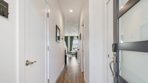 A hallway with a wooden floor, white walls, and a door with a glass panel. - Family friendly townhome + Game Room + King beds (Salem)