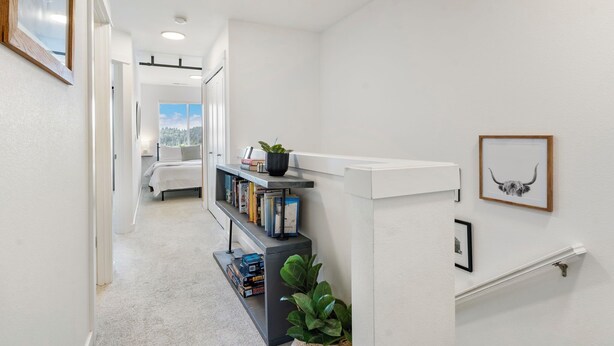 A hallway with a bookshelf, a plant, and framed pictures on the wall. - Family friendly townhome + Game Room + King beds (Salem)