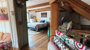Una habitación con vigas de madera, una cama, un sofá y una pared de piedra.