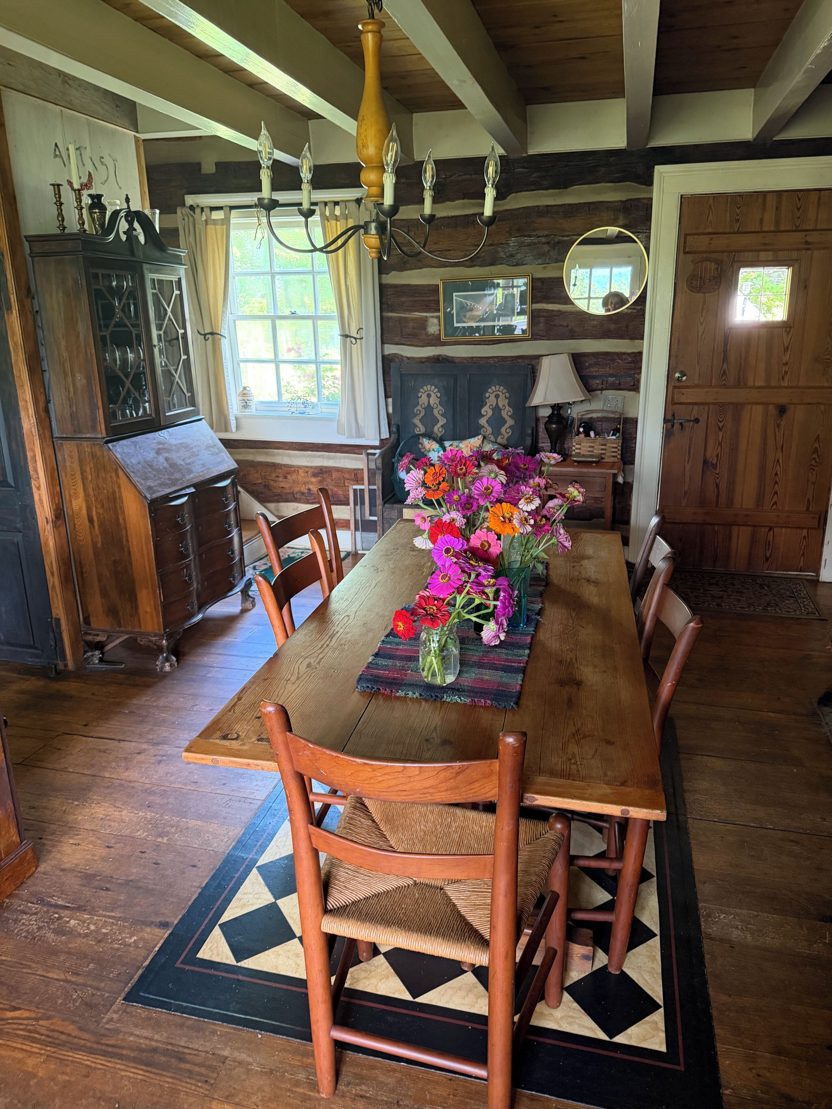 A dining area with a wooden table, chairs, and a floral centerpiece.