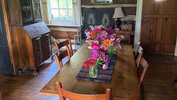 A dining area with a wooden table, chairs, and a floral centerpiece.