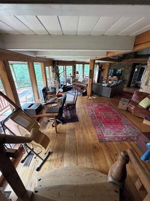 A spacious living area with a piano, a fireplace, and a large window overlooking greenery.