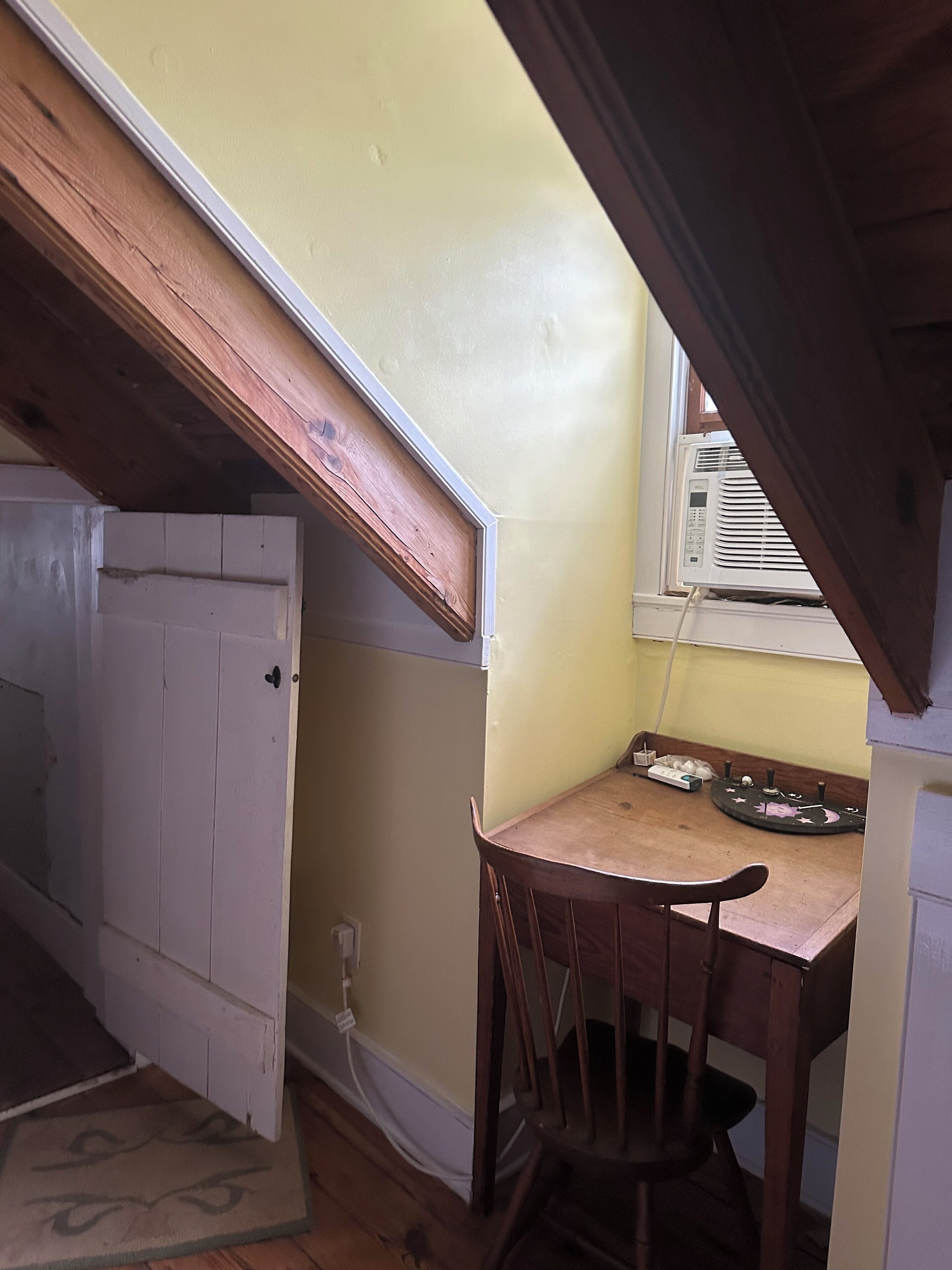 A room with a wooden ceiling, a white door, a table with chairs, and a window with blinds.