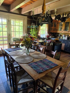 A dining area with a wooden table set for four, surrounded by chairs.