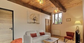 A living room with a sofa, armchairs, a coffee table, a painting, a window, and a lamp. - Le Cerf - LANGAST - Vacation Rental (LANGAST)