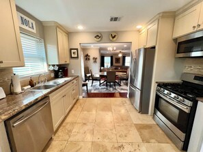 A kitchen with a refrigerator, stove, and a dining area with chairs and a table.