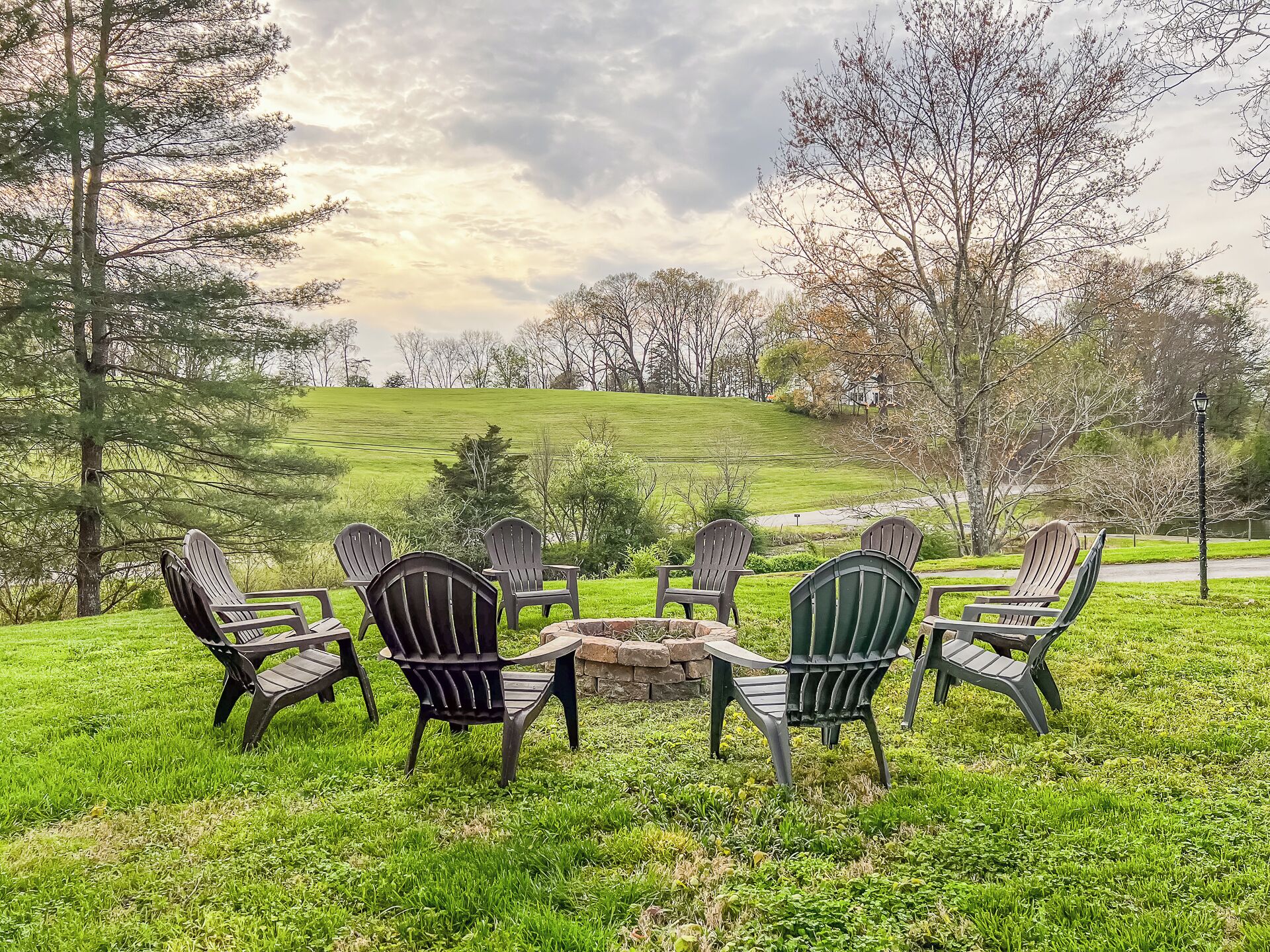 Un espace extérieur aménagé avec une pelouse, des fauteuils Adirondack et un foyer.