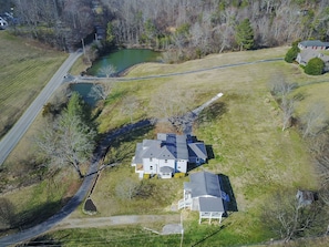 A large house with a garage, a pond, and a road.