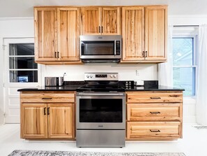 A kitchen with wooden cabinets, a microwave, a stove, and a dishwasher.