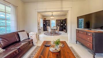 A spacious living room with a brown leather sofa, a wooden coffee table, and a TV stand.