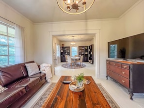 A spacious living room with a brown leather sofa, a wooden coffee table, and a TV stand.